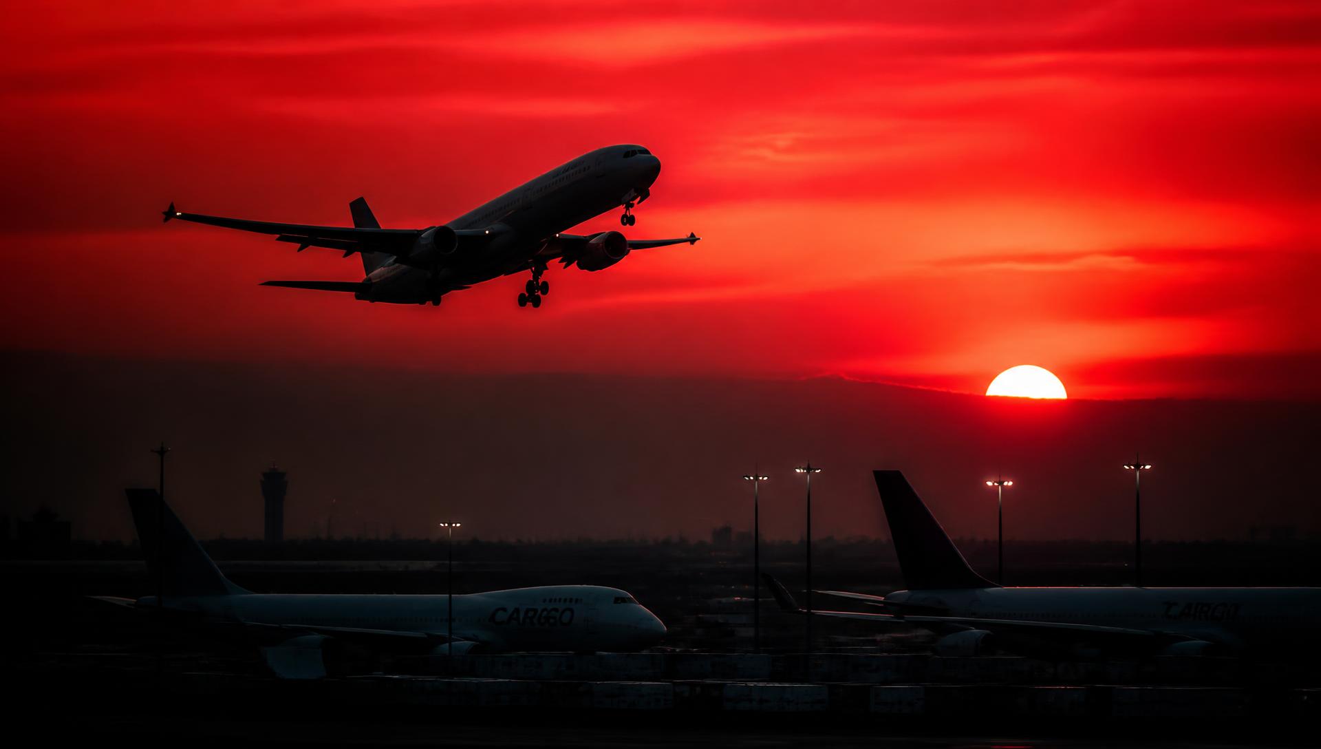 Aircraft departing at sunrise above a cargo terminal